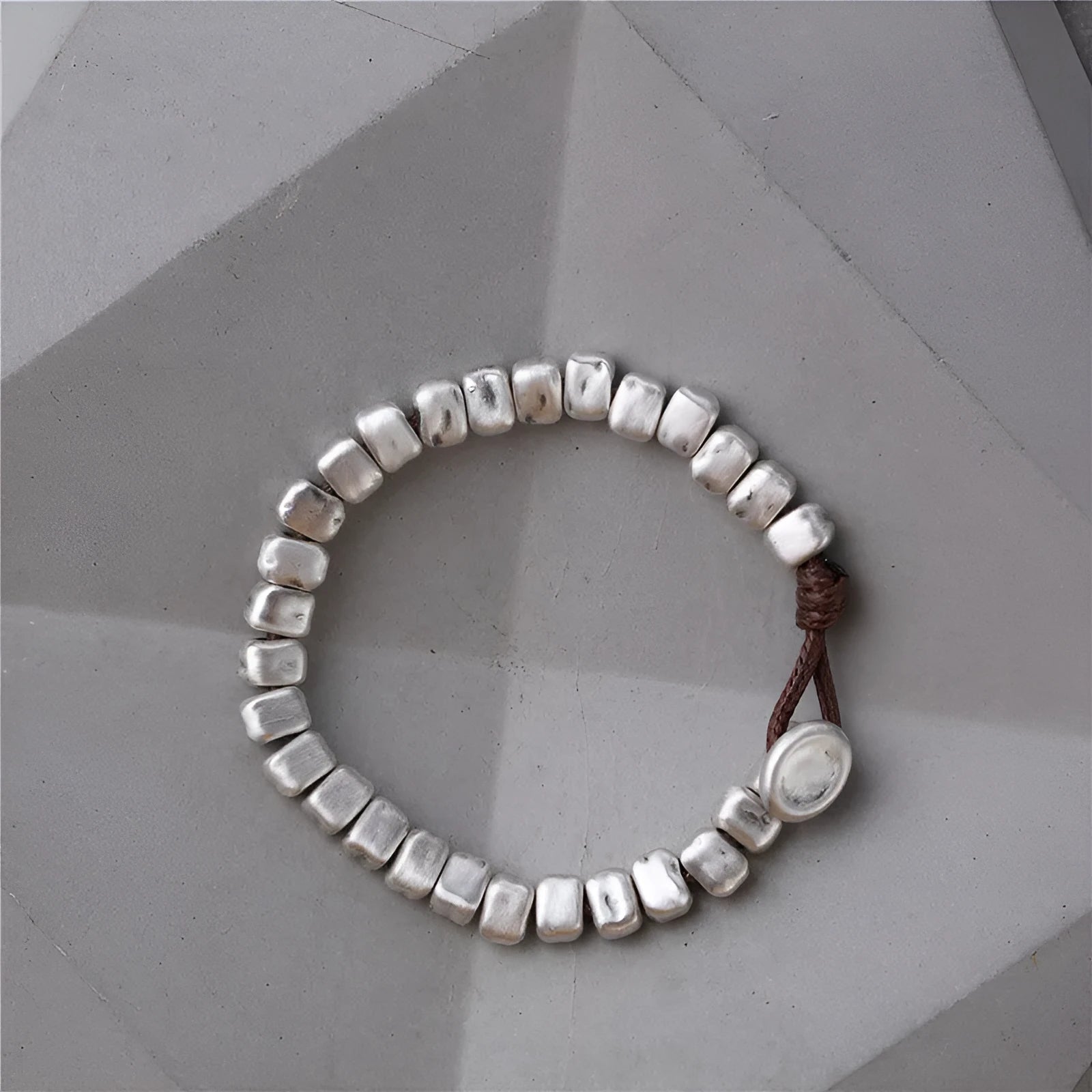 Handmade silver bracelet with an irregular square design and wooden details on an elasticated band.