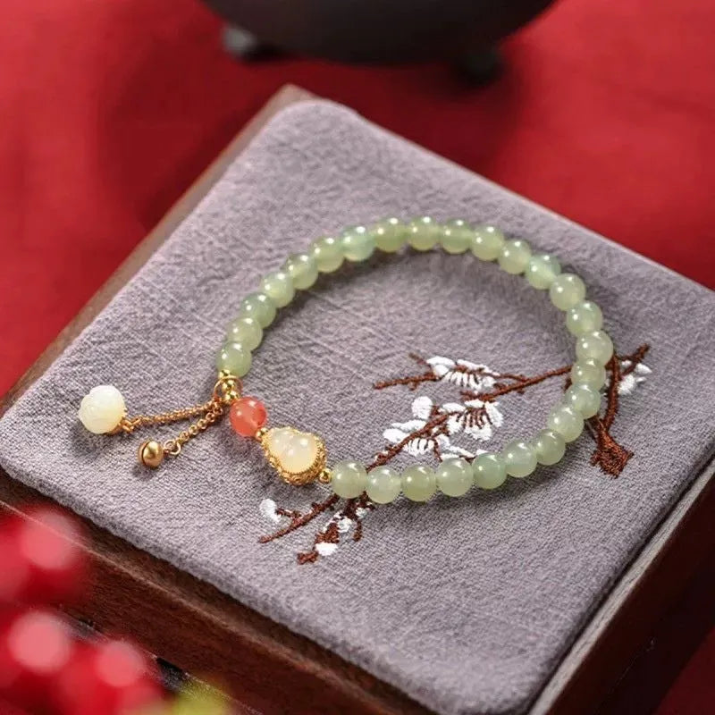 Natural jade bracelet with a gold-plated gourd charm and fu character charm.