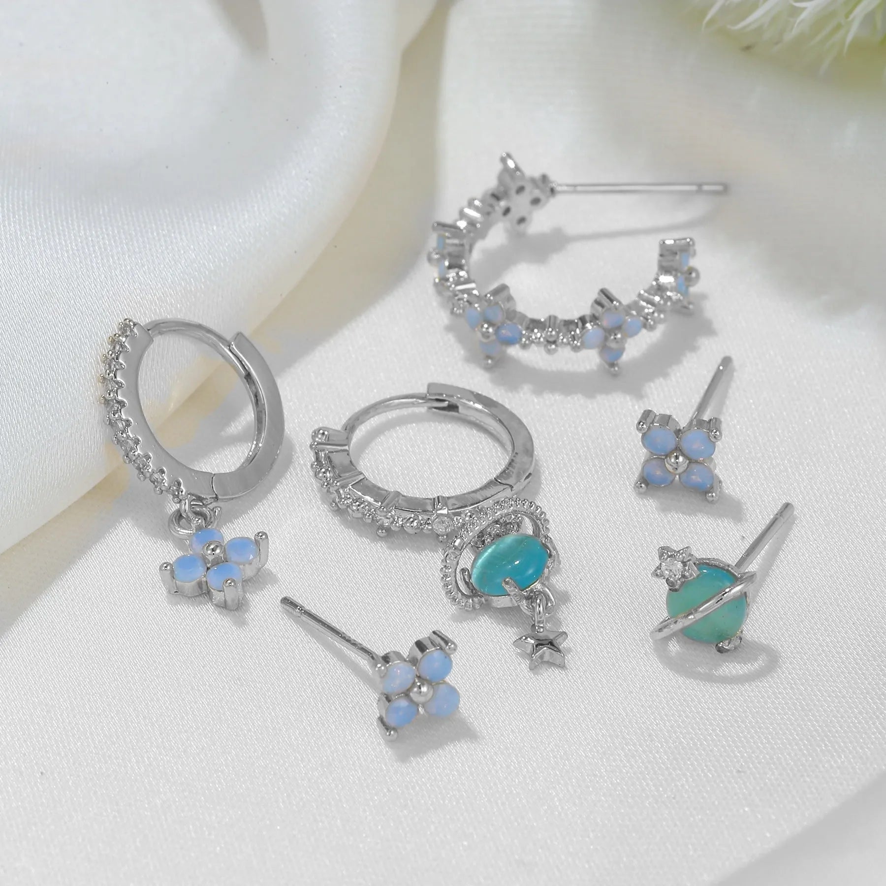 Gold and silver flower-shaped ear studs with blue zircon mosaic decoration.