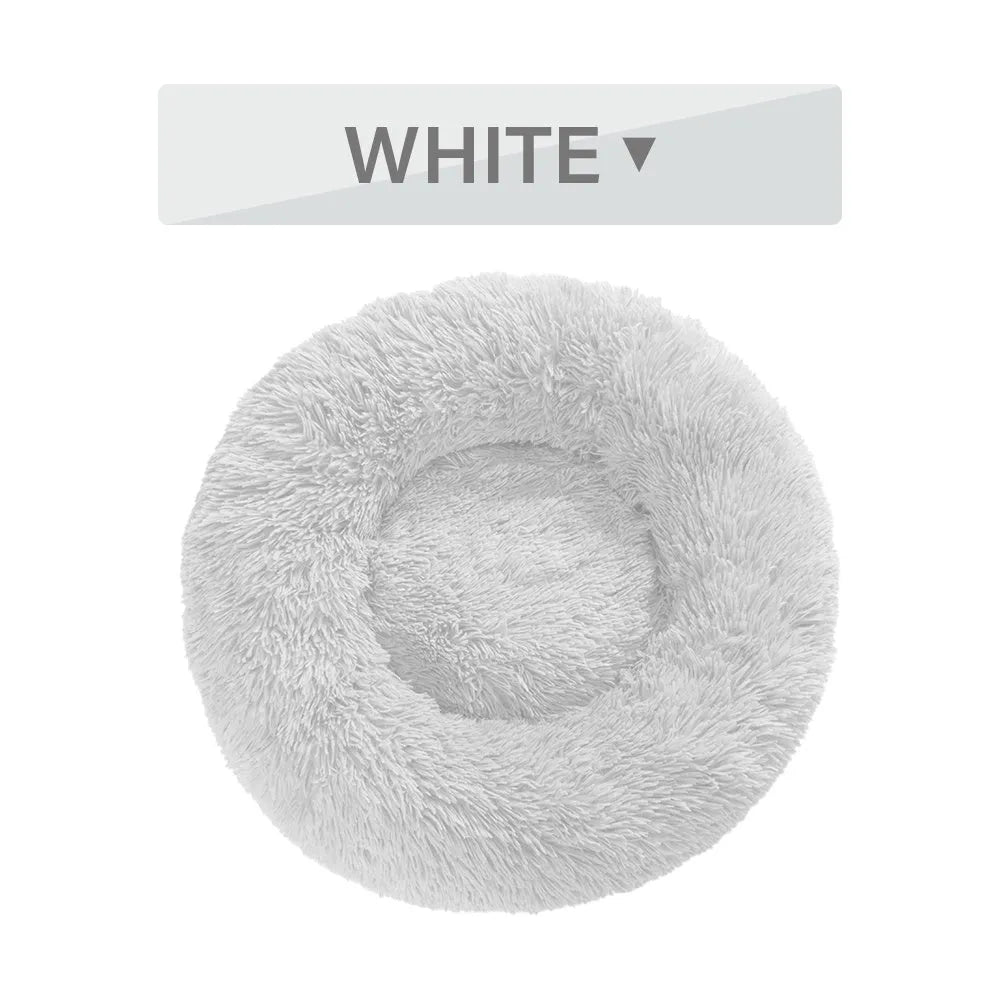 Fluffy donut-shaped dog bed in long plush fabric, shown in a light grey colour with raised edges.
