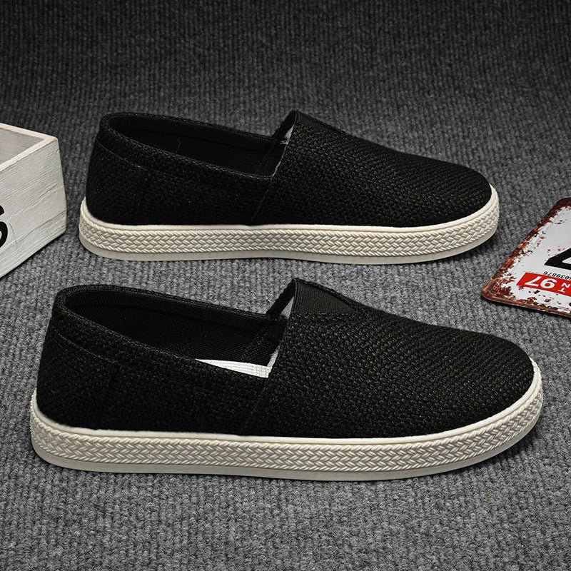 Men's beige canvas slip-on loafers with a round toe and shallow cut on a plain background.