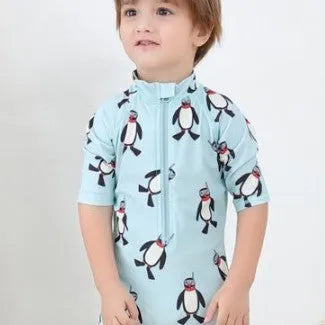 Boy's long sleeve penguin print swimsuit and matching swim cap set on a white background