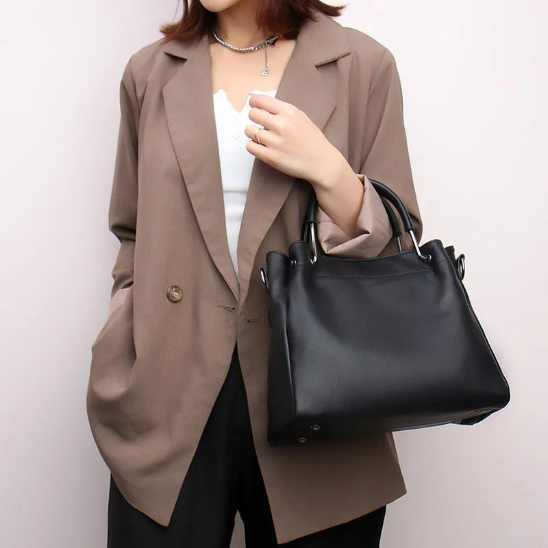 Soft PU leather bucket bag in black with visible sewing thread and external slit pocket