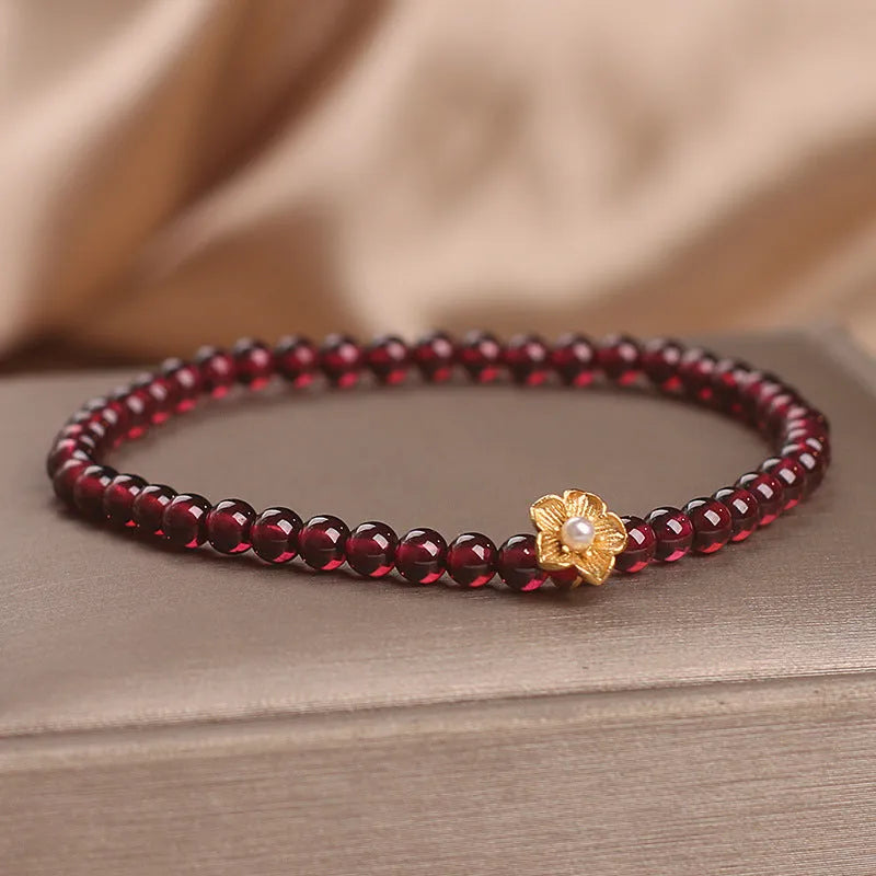Red stone bead string bracelet with yellow flower accessories on wrist