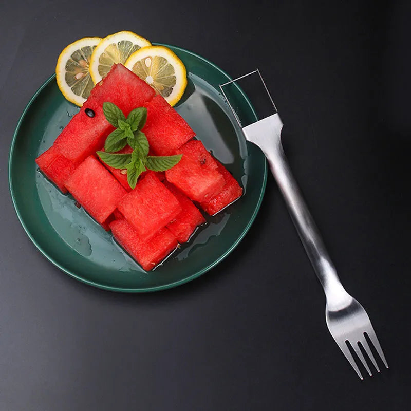 Silver stainless steel watermelon slicer and serving fork with a long handle on a kitchen surface