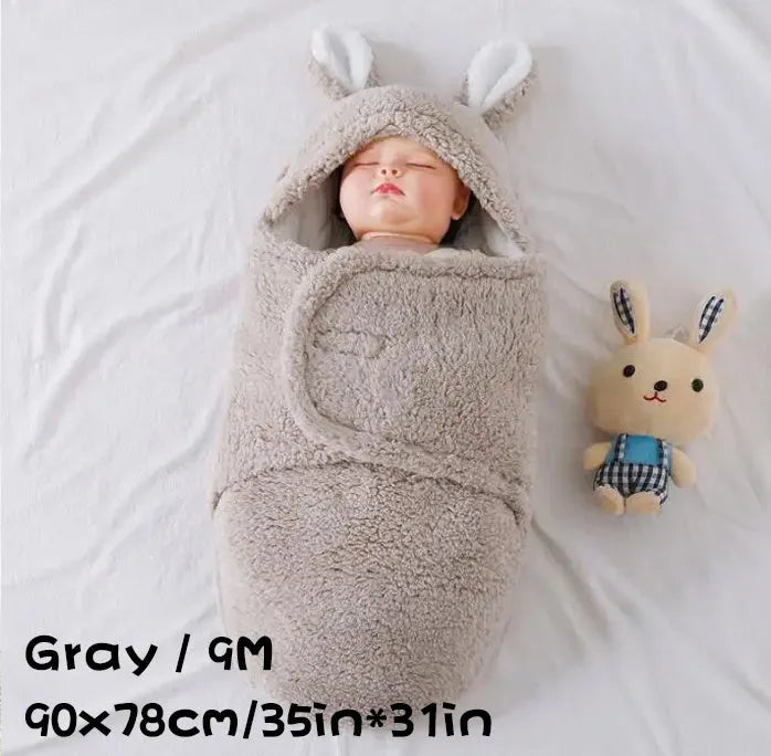 A baby wearing a soft grey fleece sleeping bag with hook-and-loop shoulder straps.