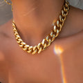 Gold-coloured thick chain necklace for women on a plain background
