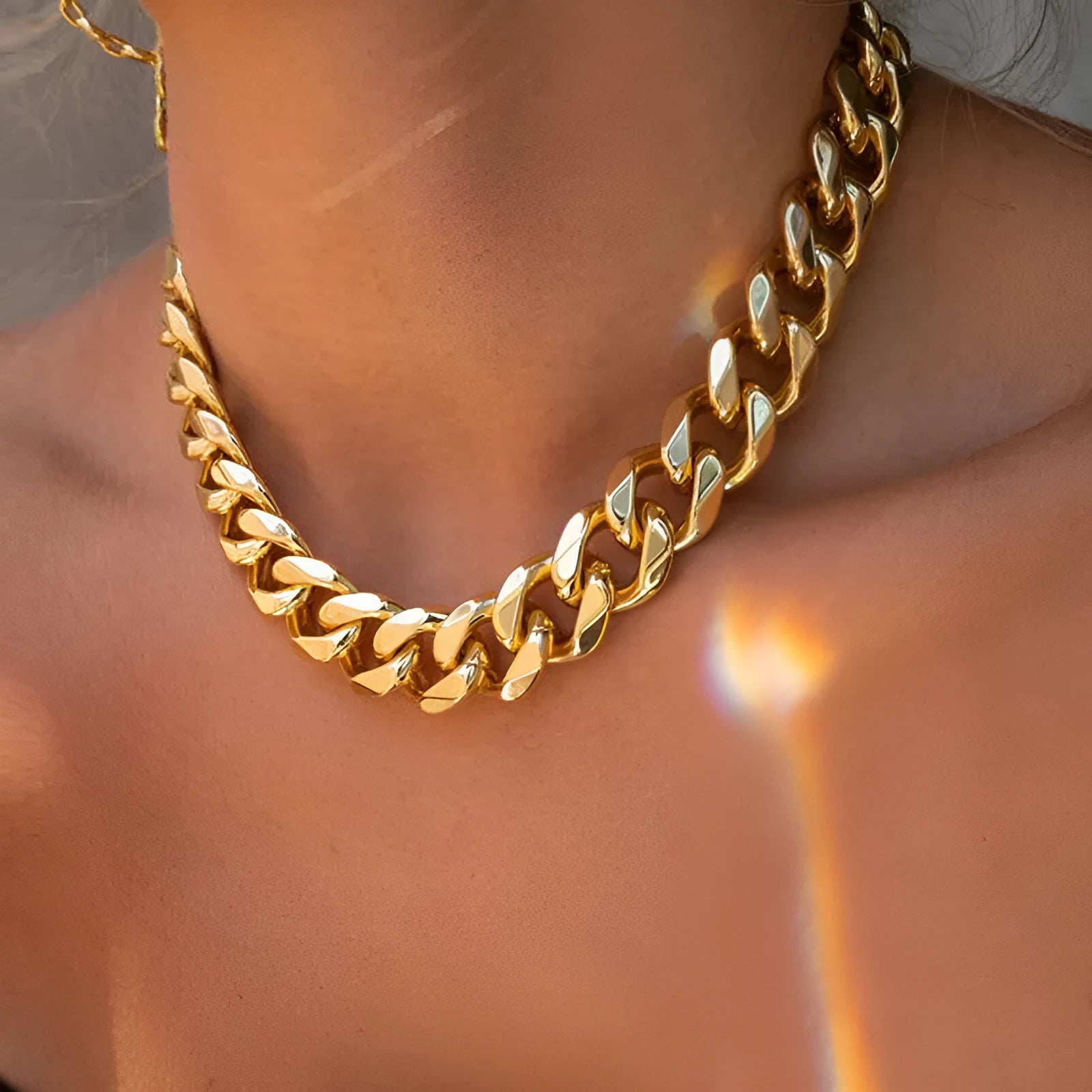 Gold-coloured thick chain necklace for women on a plain background