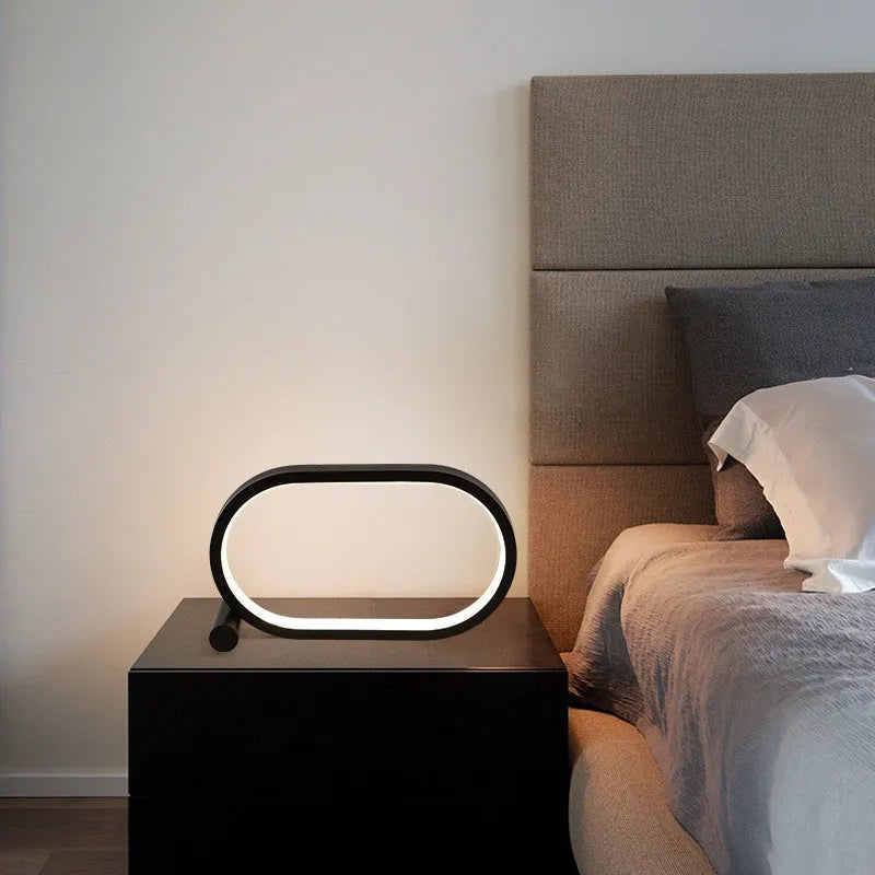 USB plug-in oval acrylic touch lamp with dimmable LED, metal body, on a bedside table