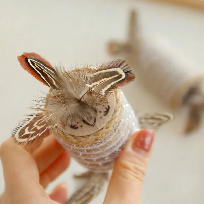 Beige cat toy made of hemp rope with feathers and an integrated roller for scratching and play