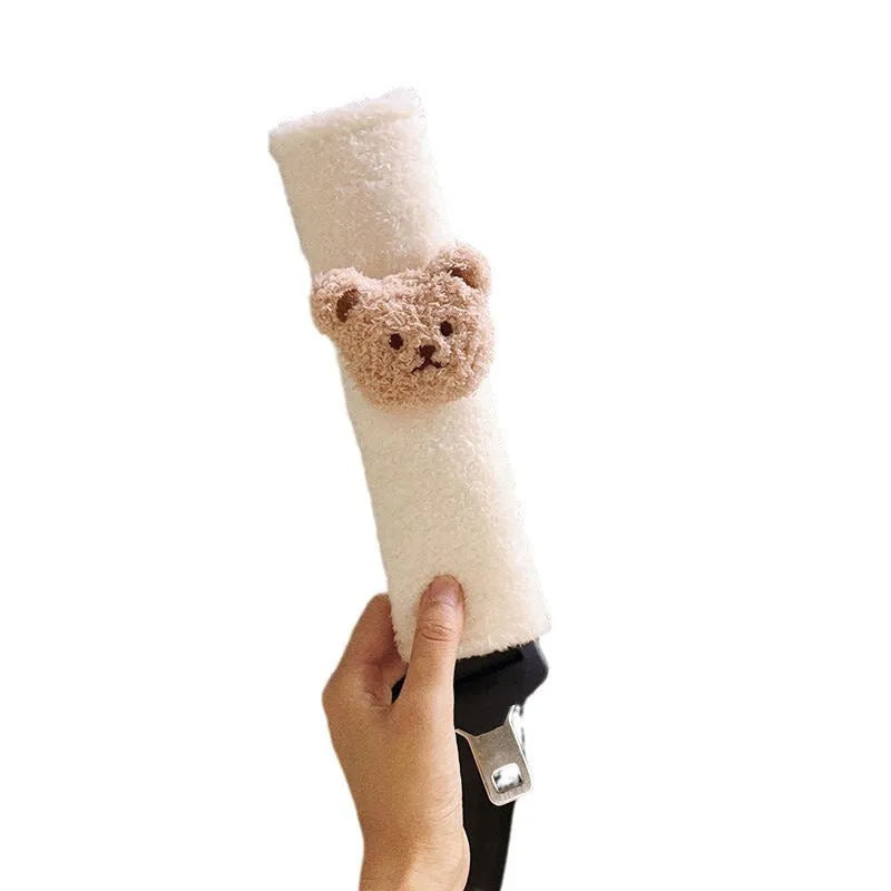 Close-up of a khaki-coloured plush bear seat belt cover on a car seat strap.
