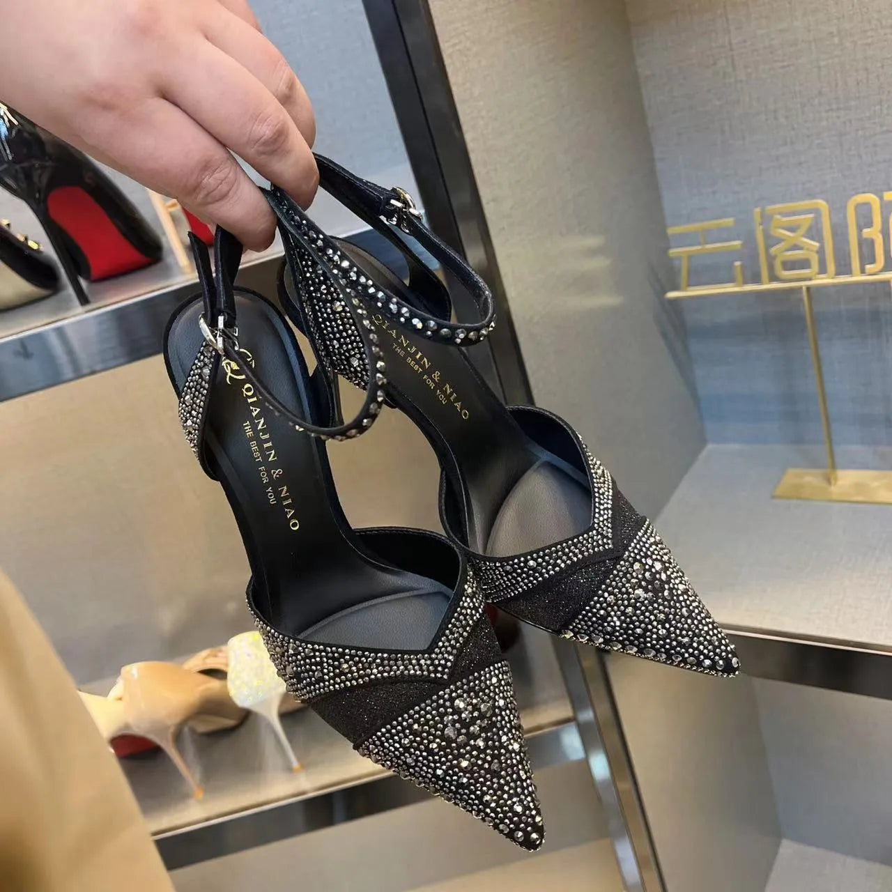 Women's black high heels with hollow design, red sole, and pointed toe on stiletto heel