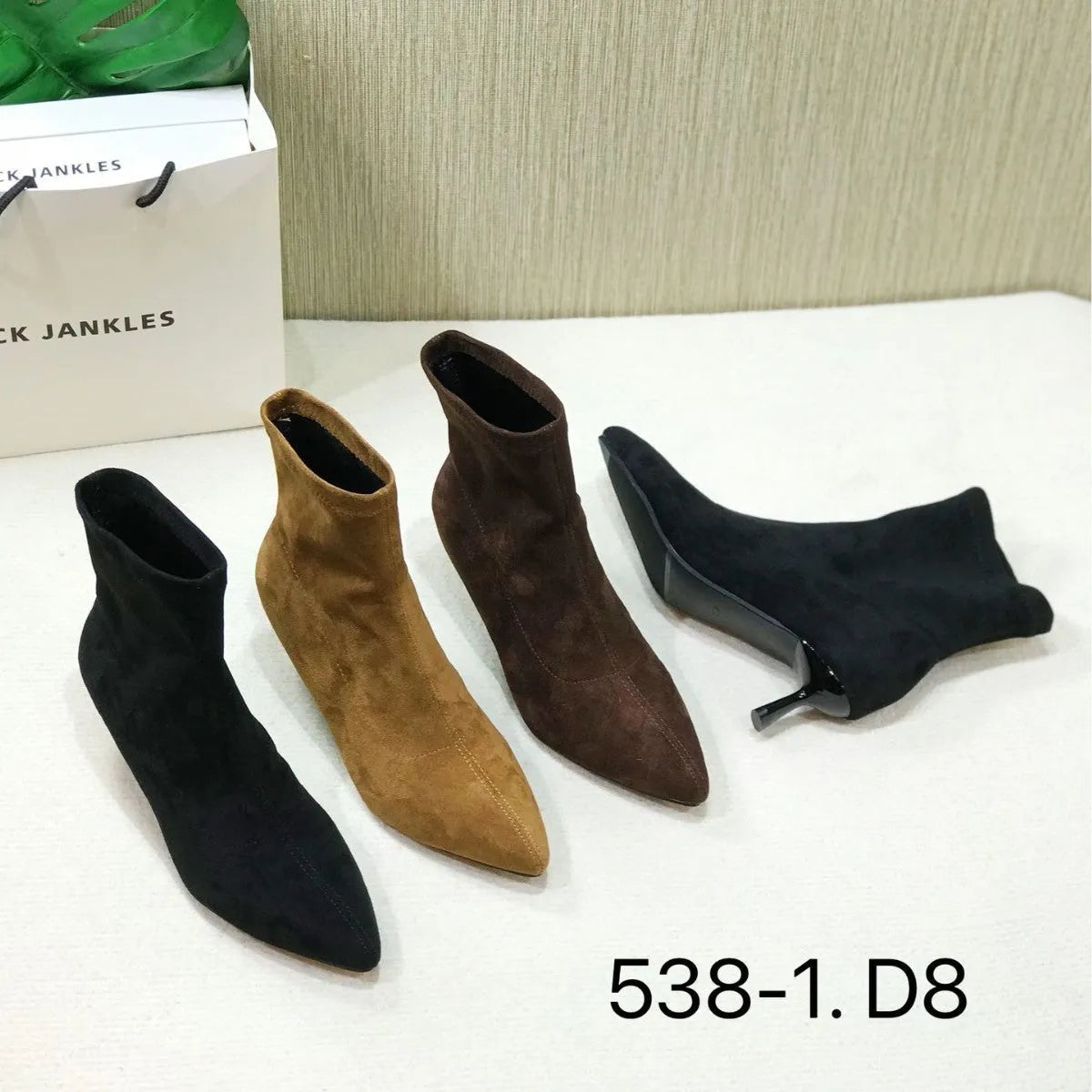 Black microfiber ankle boots with a stiletto heel and pointed toe on a mid-calf sock.