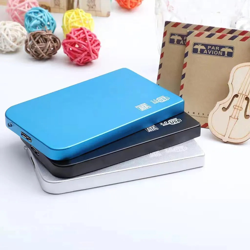 Silver portable solid state drive with USB cable and cover on a desk.