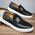 Black men's slip-on loafers with tassel detail and rubber sole, shown in profile view