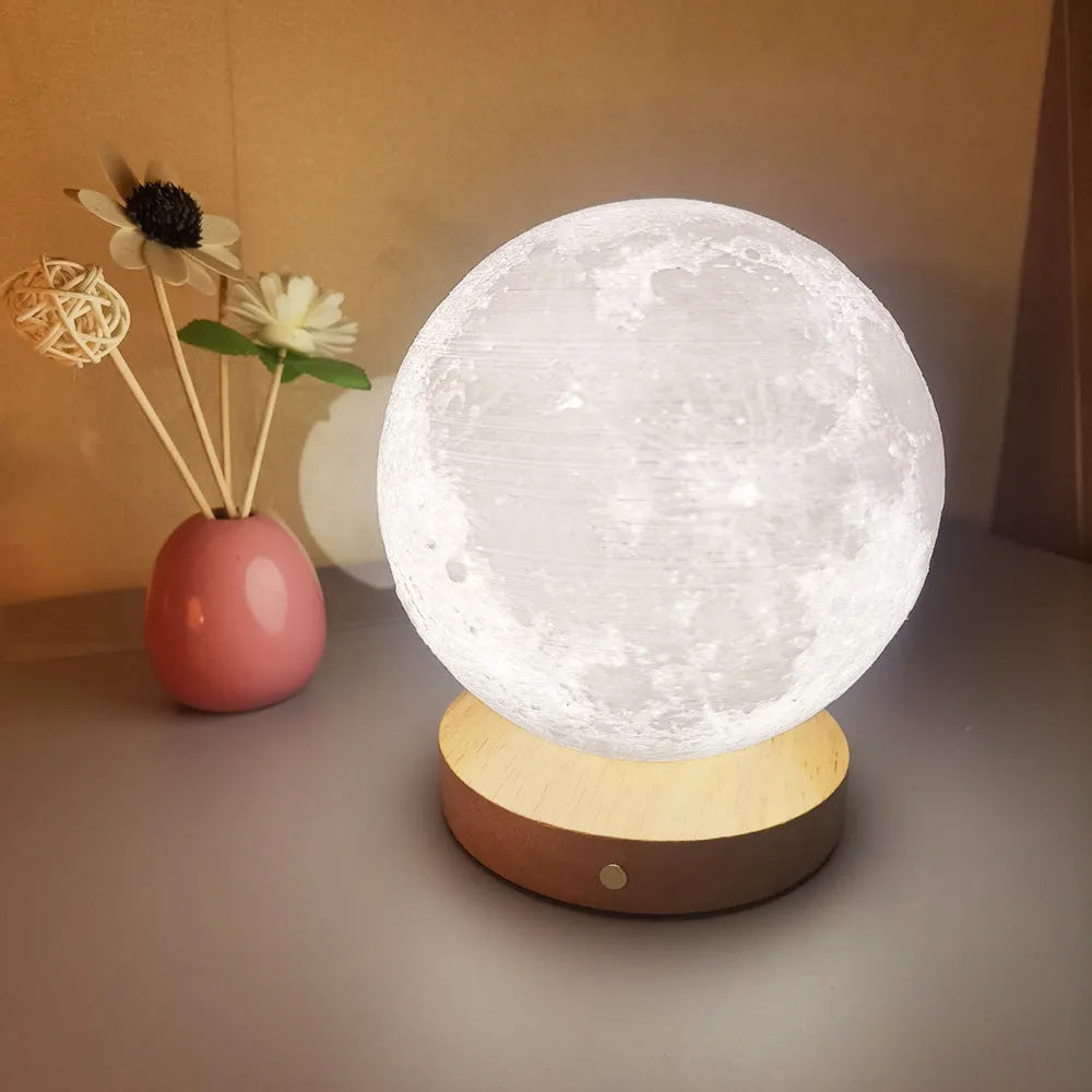 Rotating moon night lamp with wooden base on a table, showing three colour settings and remote control.