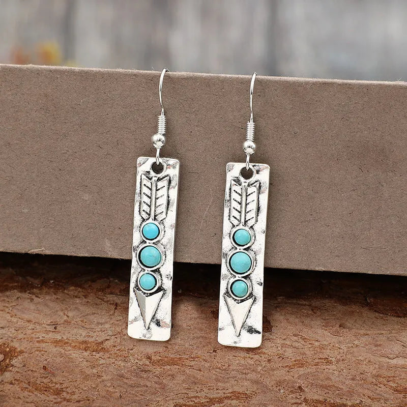 Silver geometric drop earrings with turquoise inlays and retro styling on white background