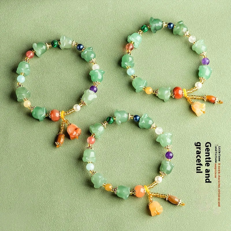 Natural Xinjiang Jinsi Jade bracelet with carved aventurine orchid beads on a wrist.