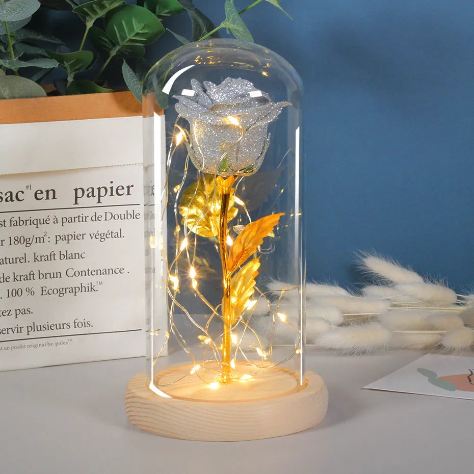 Glass dome containing red eternal roses illuminated by a warm white bendable LED light string.