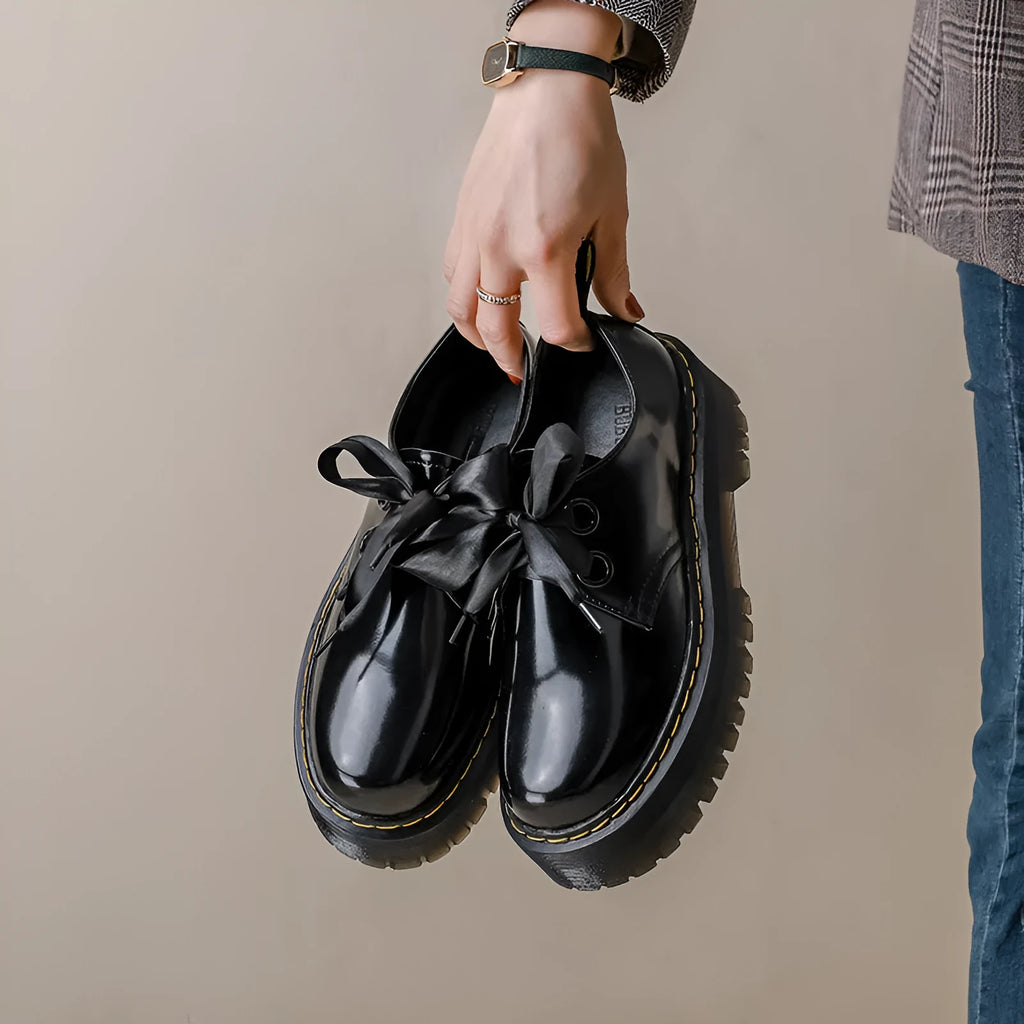 Black and white women's lace-up shoes with a thick sole, cross straps, and ribbon details.