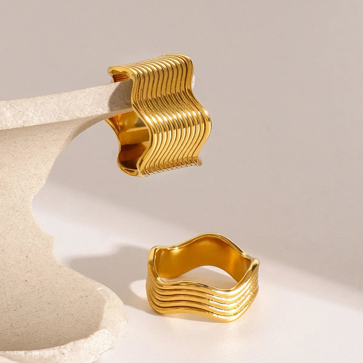 Stainless steel women's ring with a wide geometric wave pattern design on a hand.