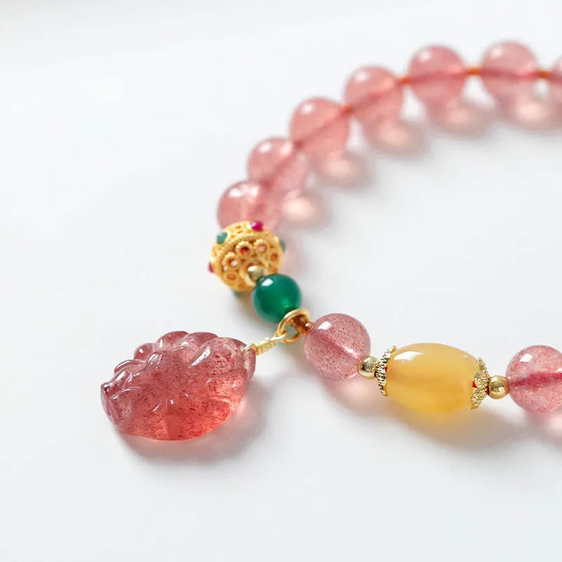Women's Nine Tail Fox style strawberry quartz crystal beaded bracelet on wrist.