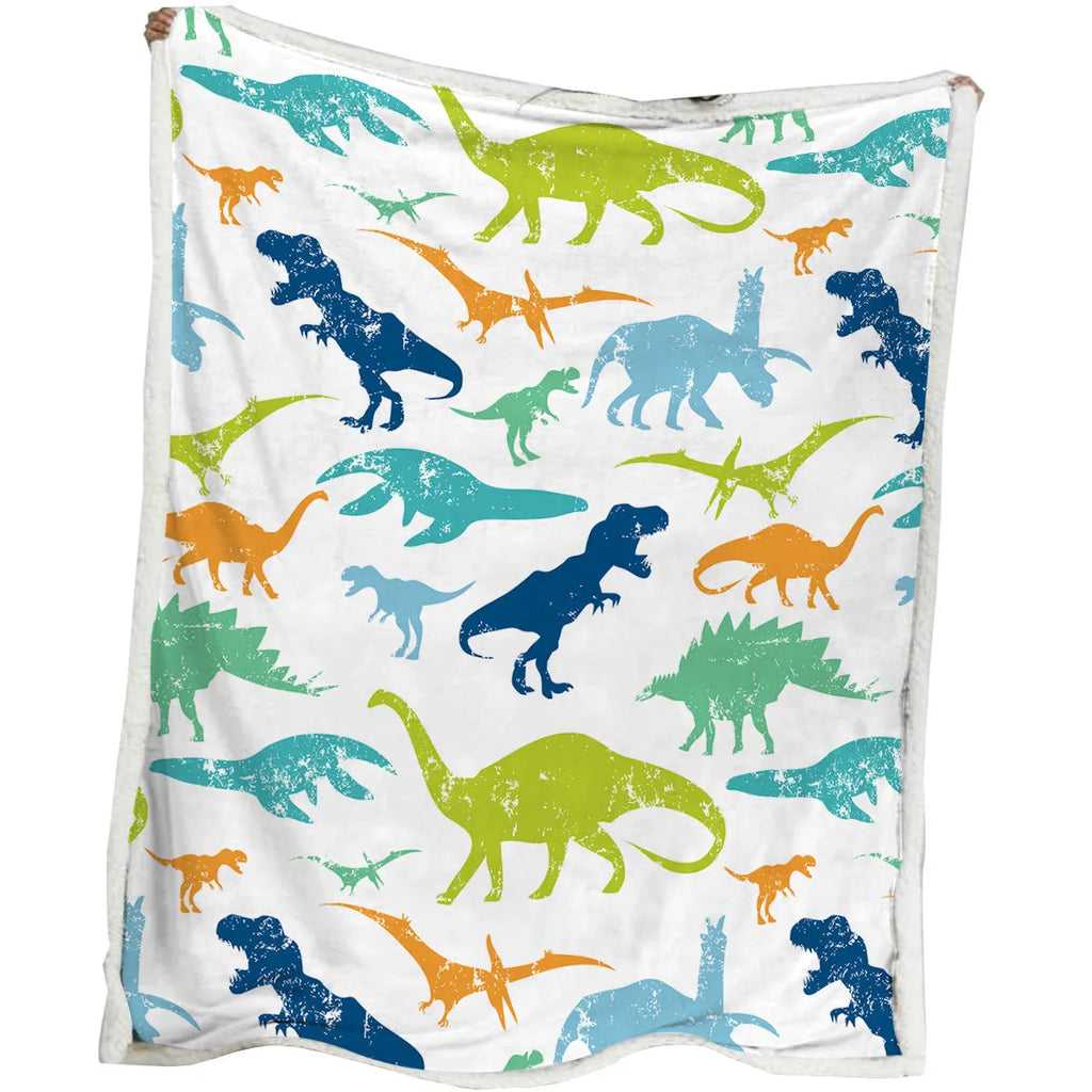 Dinosaur themed white sherpa fleece lamb wool blanket folded on a sofa