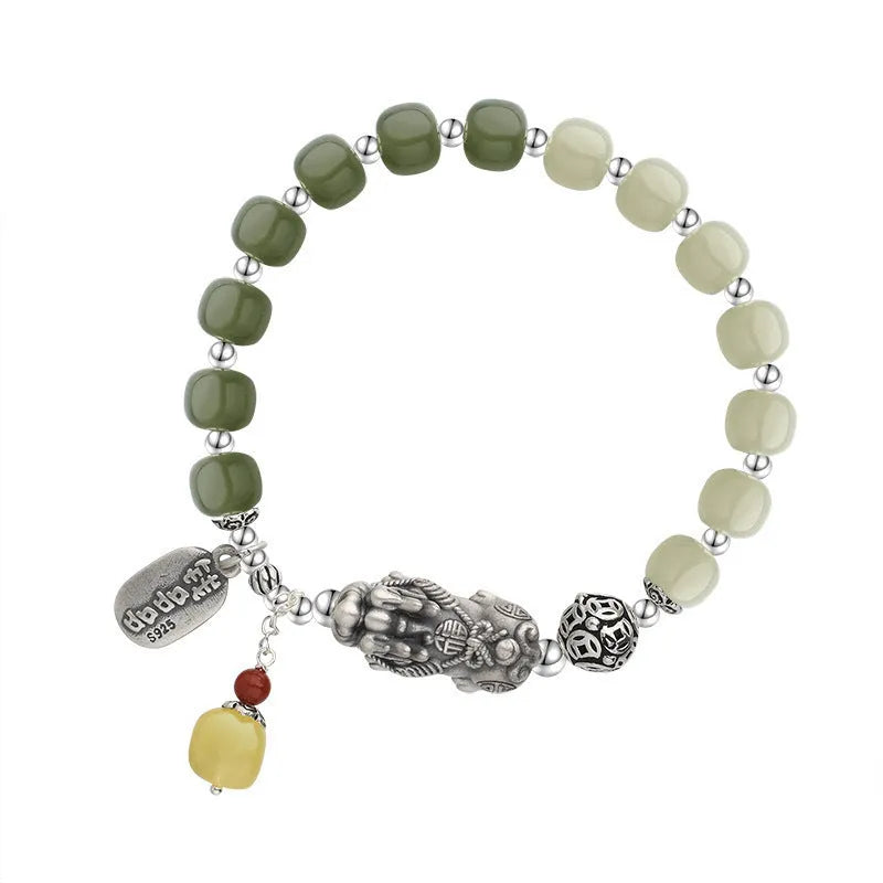 Close-up of a women's silver bracelet with Hetian jade beads and an 8x7mm retro coin charm.