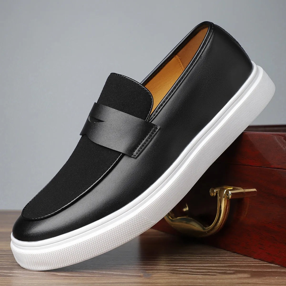 Black men's slip-on loafers with tassel detail and rubber sole, shown in profile view