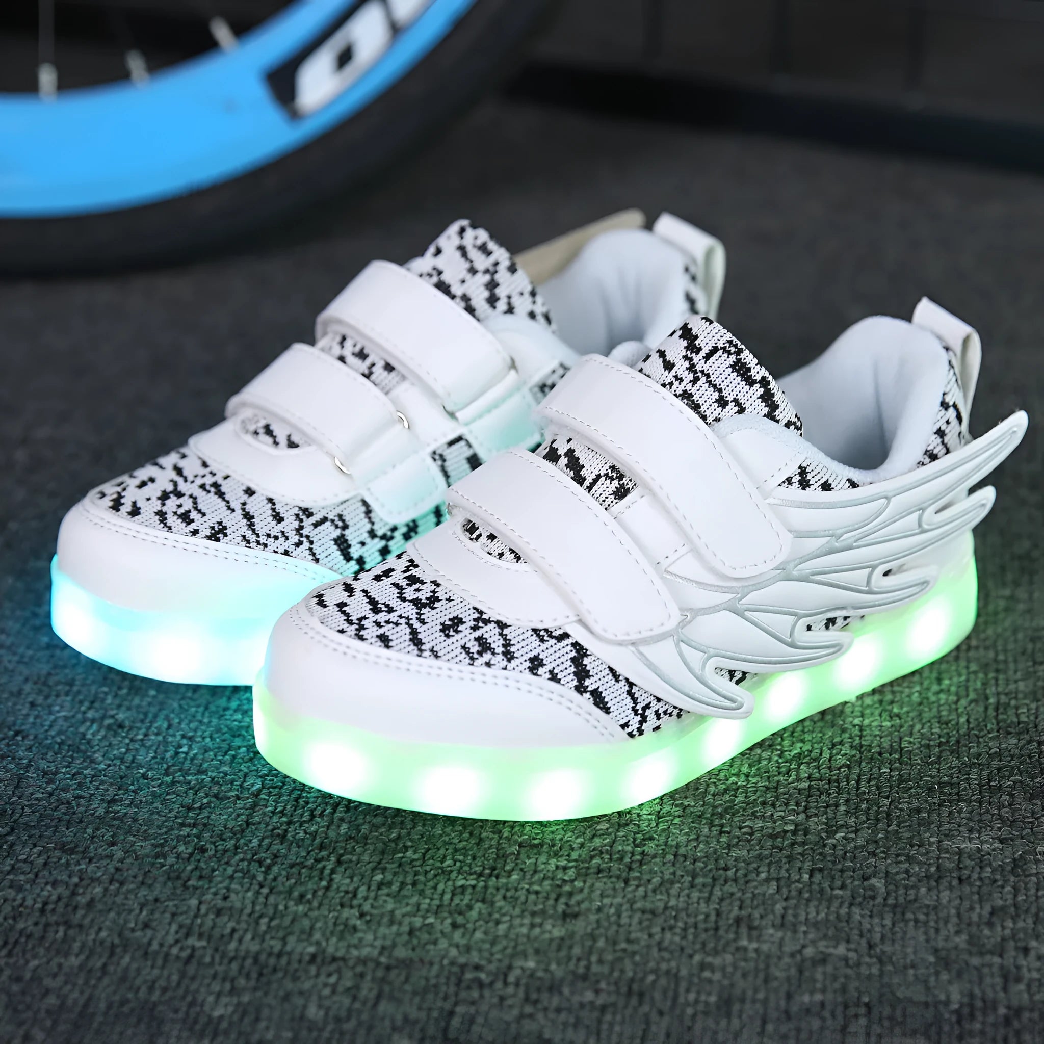 Children's plum red and white LED light-up sneakers with colourful winged lights, showing USB charging port.
