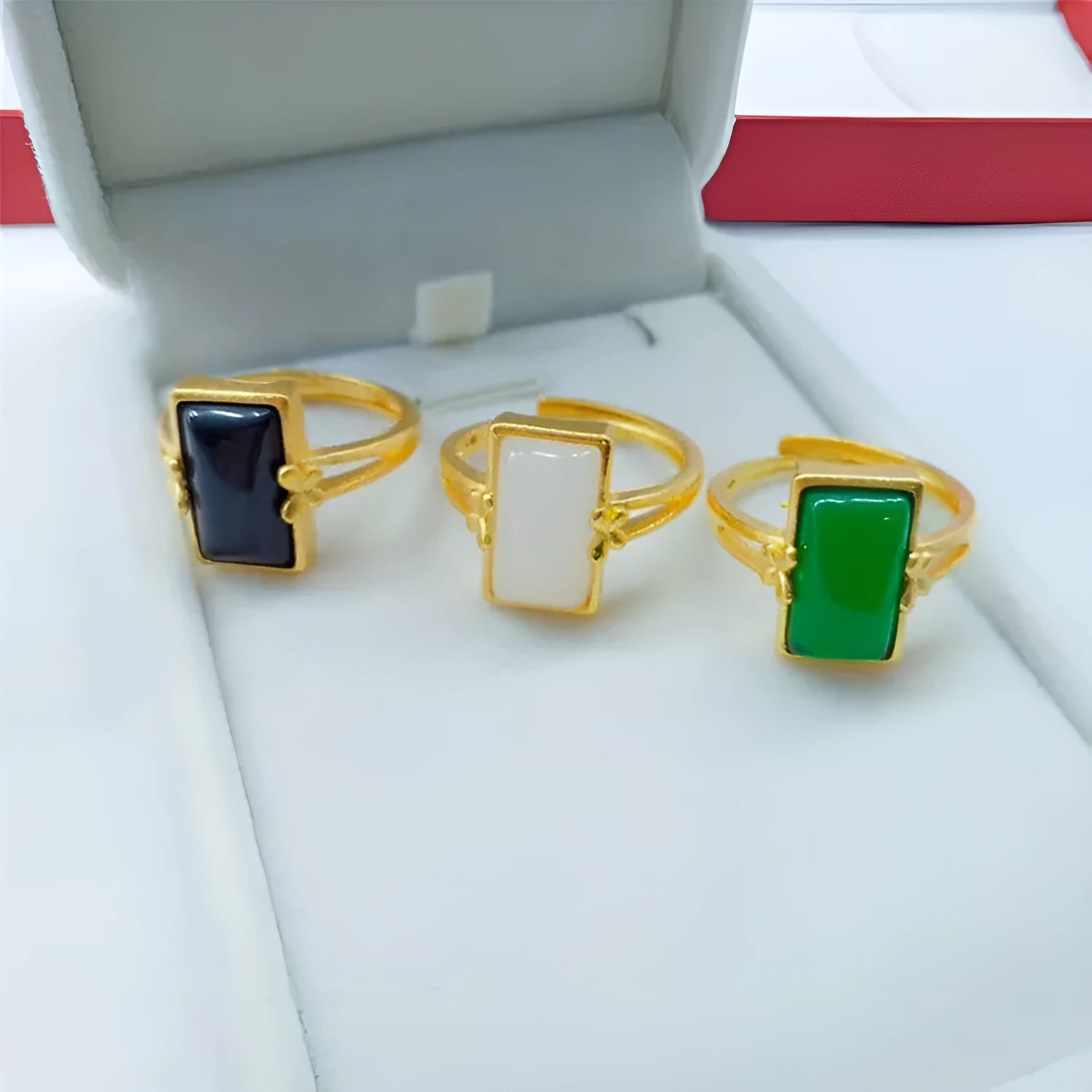 A gold-coloured adjustable ring with a large central green artificial gemstone, showing the national style design.