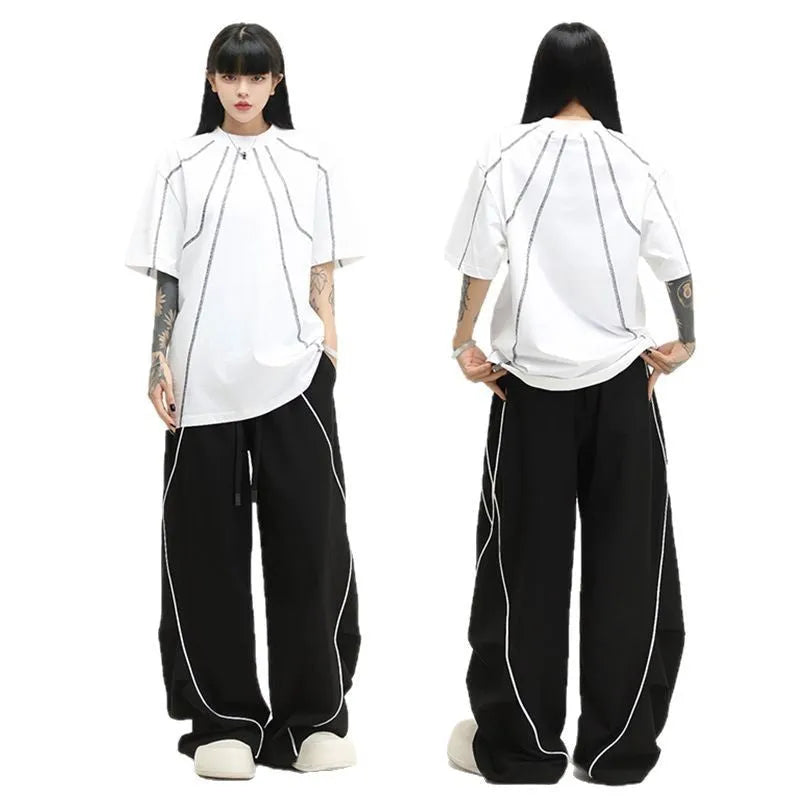 Black trousers with vertical stripes and pleated detail on the legs, showing a loose wide-leg fit.
