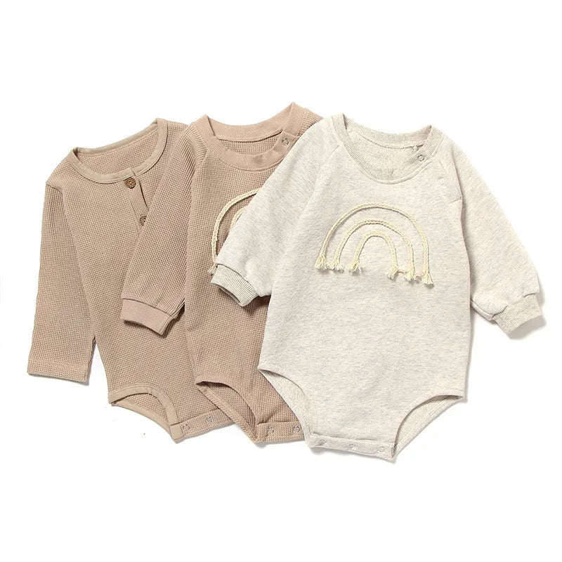Neutral baby romper in waffle cotton fabric with long sleeves, shown in beige with cotton rope detail.