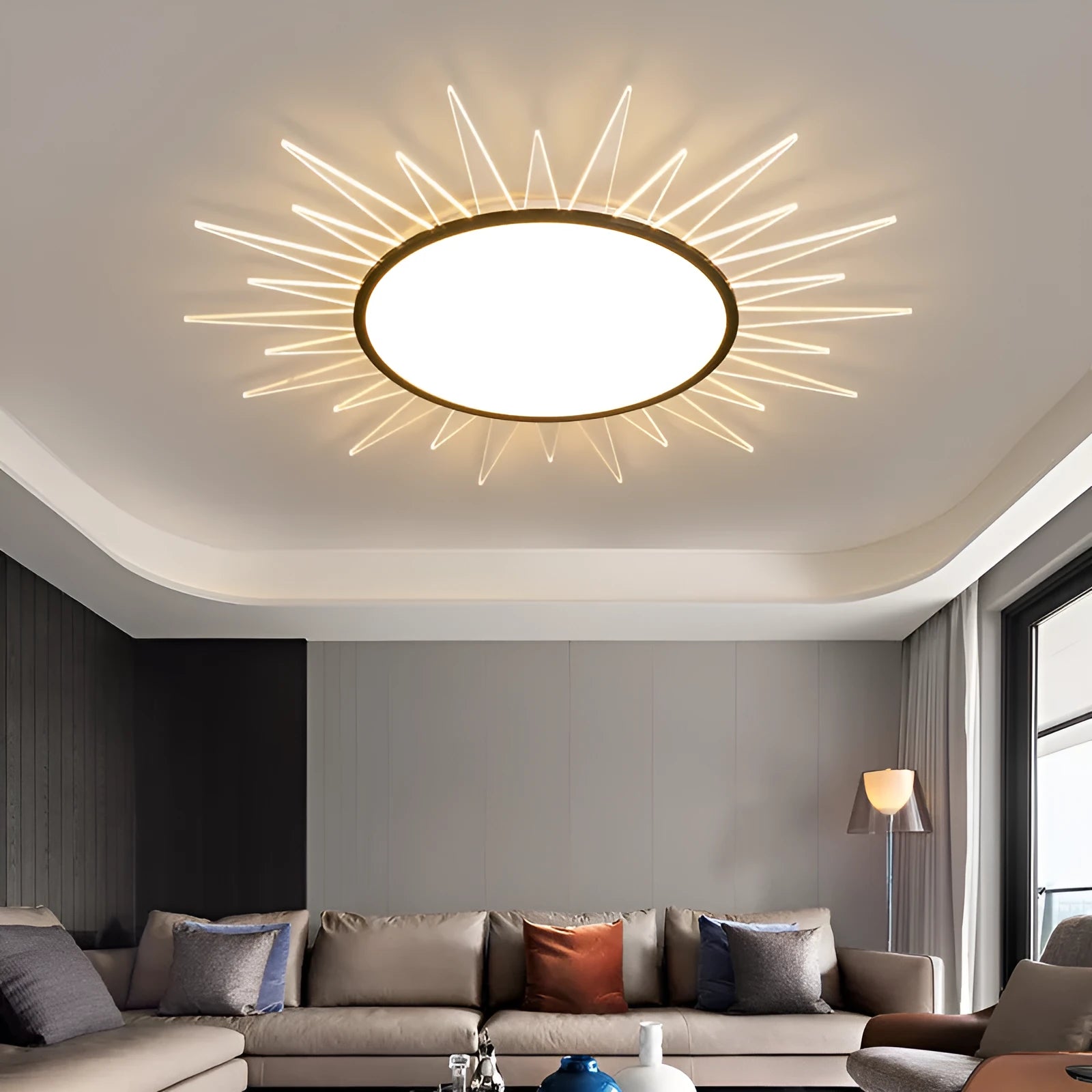 Modern round aluminium LED ceiling lamp with remote control for dimming, shown in a living room setting.