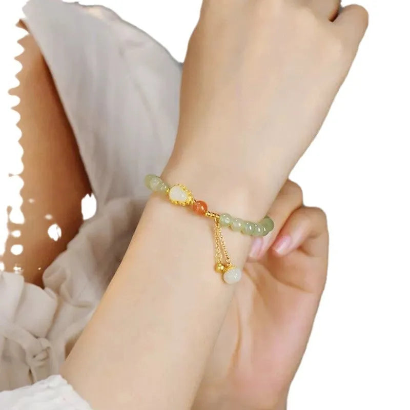 Natural jade bracelet with a gold-plated gourd charm and fu character charm.