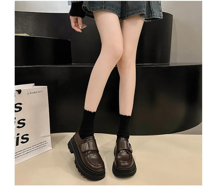 Women's black chunky heel shoes with low top, round toe, and cross strap detail on a white background