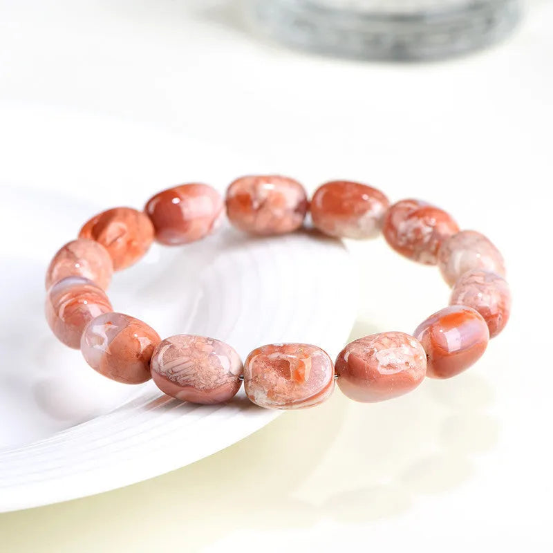 Natural cherry agate barrel bead bracelet with Ruyi symbol on a wrist.