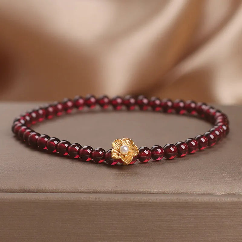 Red stone bead string bracelet with yellow flower accessories on wrist