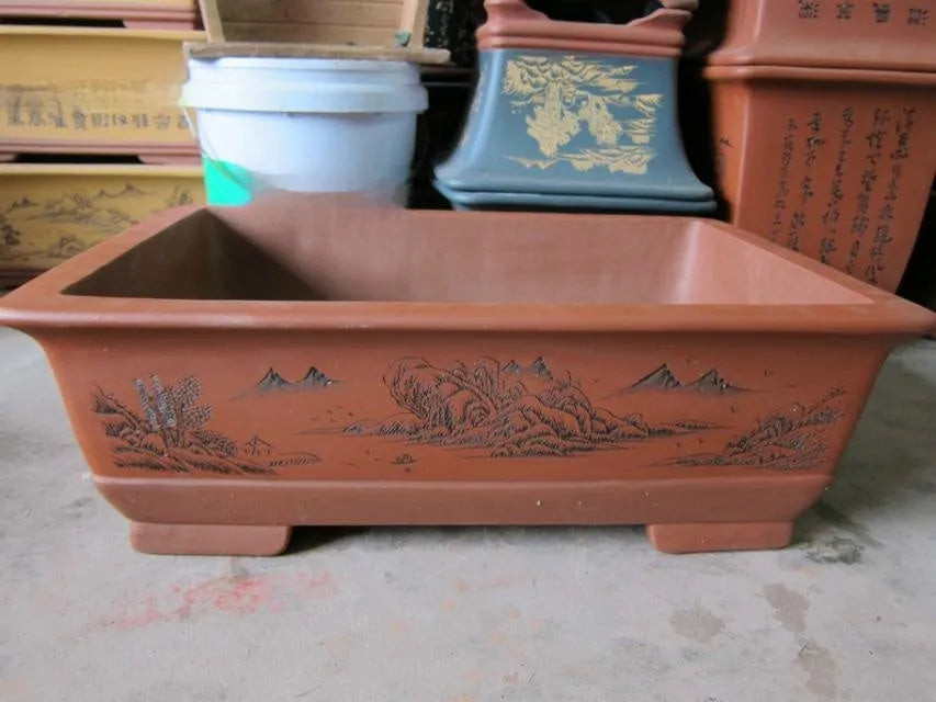 Two Yixing purple clay rectangular flower pots in different sizes on a wooden surface