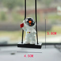 Resin astronaut car pendant showing cartoon astronaut designs including telescope, red flag, and radish variations