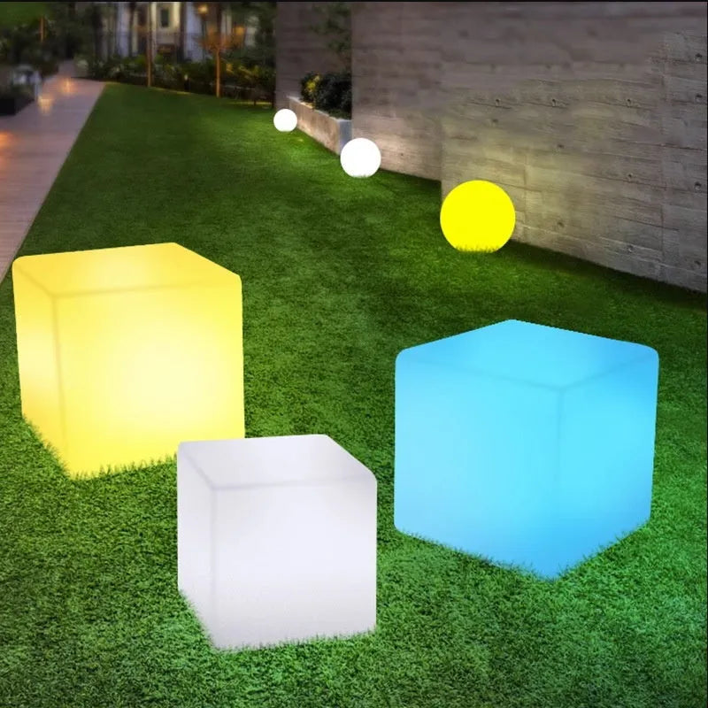 Modern square LED cube stool light outdoors, functioning as both a garden seat and a waterproof light source.