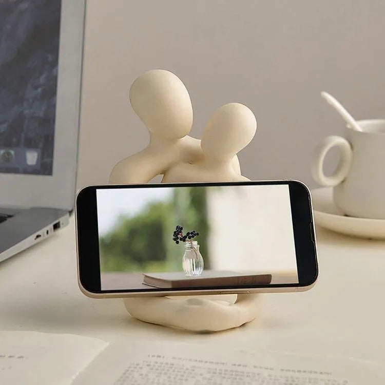 Modern milky white loving couple resin statue on a wooden shelf.