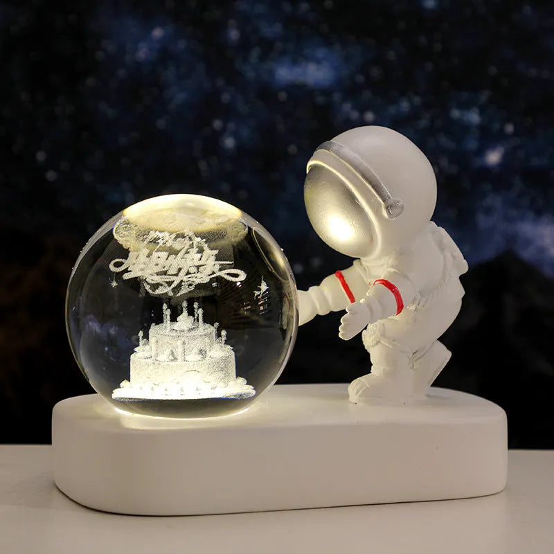 Small clear resin ball night light with glowing astronaut and galaxy scene inside on dark surface