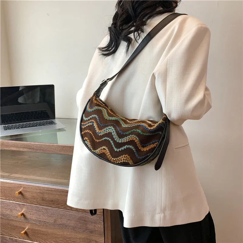 Women's straw woven crossbody bag showing woven texture and adjustable strap with internal phone and document pockets