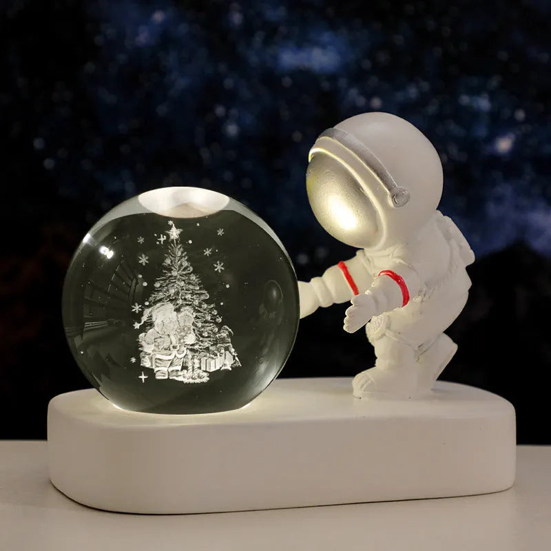 Small clear resin ball night light with glowing astronaut and galaxy scene inside on dark surface
