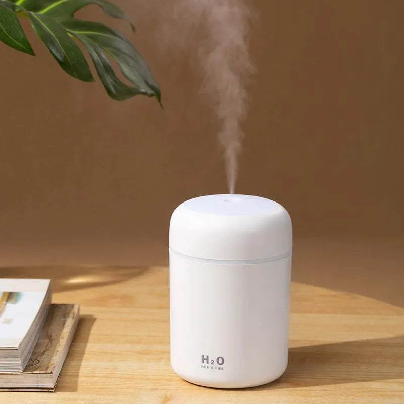 Pink, white, or navy blue USB mini desktop humidifier with atmosphere lights on a desk.