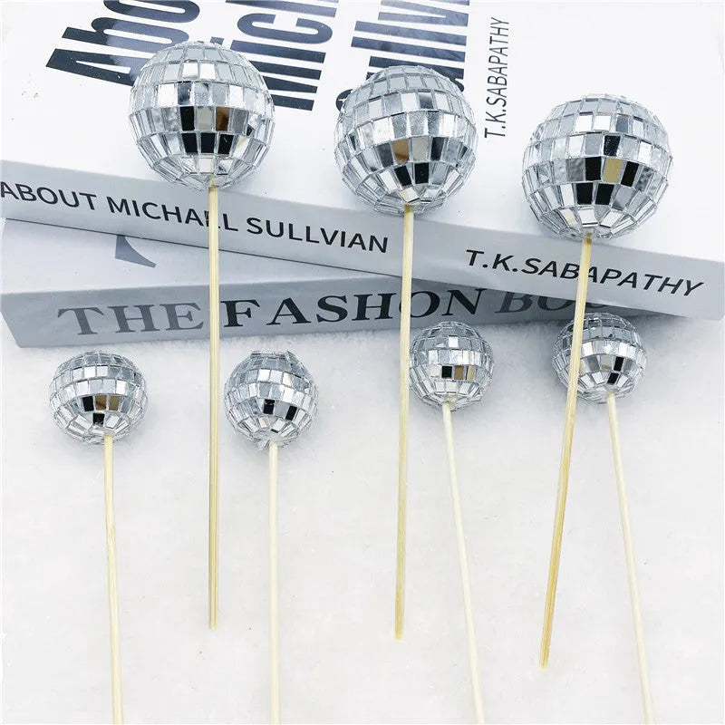 Glass mirrored disco ball cake decoration on a wooden stick, shown in different sizes.
