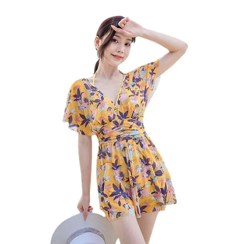 Yellow floral patterned women's one-piece swimsuit on a hanger, showing front design.