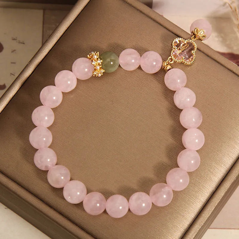 Pink women's bracelet with a crystal four-leaf clover pendant and rhinestone details on an adjustable chain.