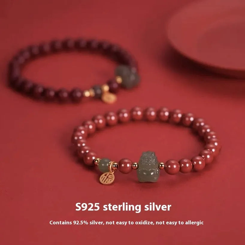 Natural Hetian Jade bracelet with cinnabar detail and zodiac charm on wrist.